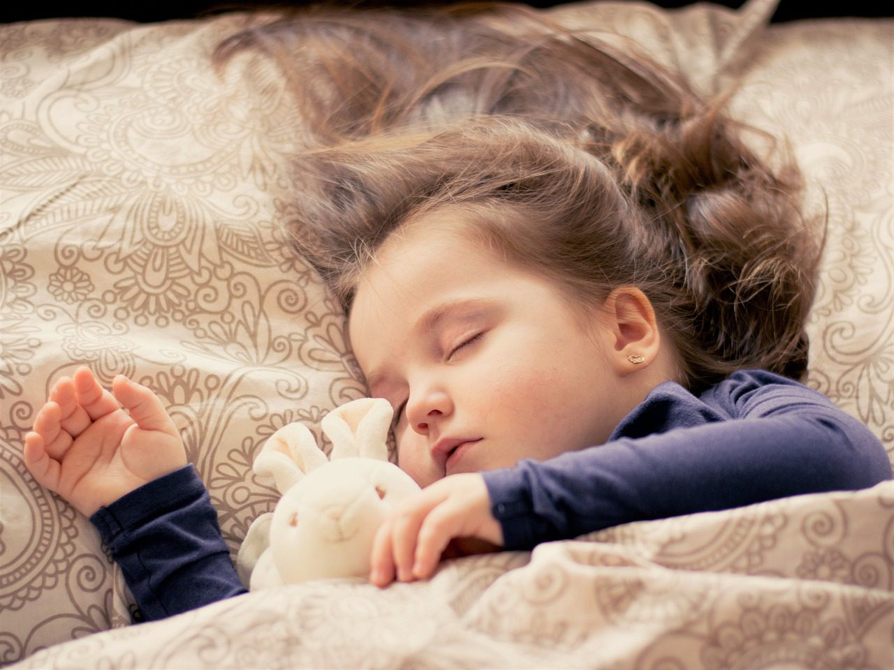 A little girl sleeping on top of the bed.