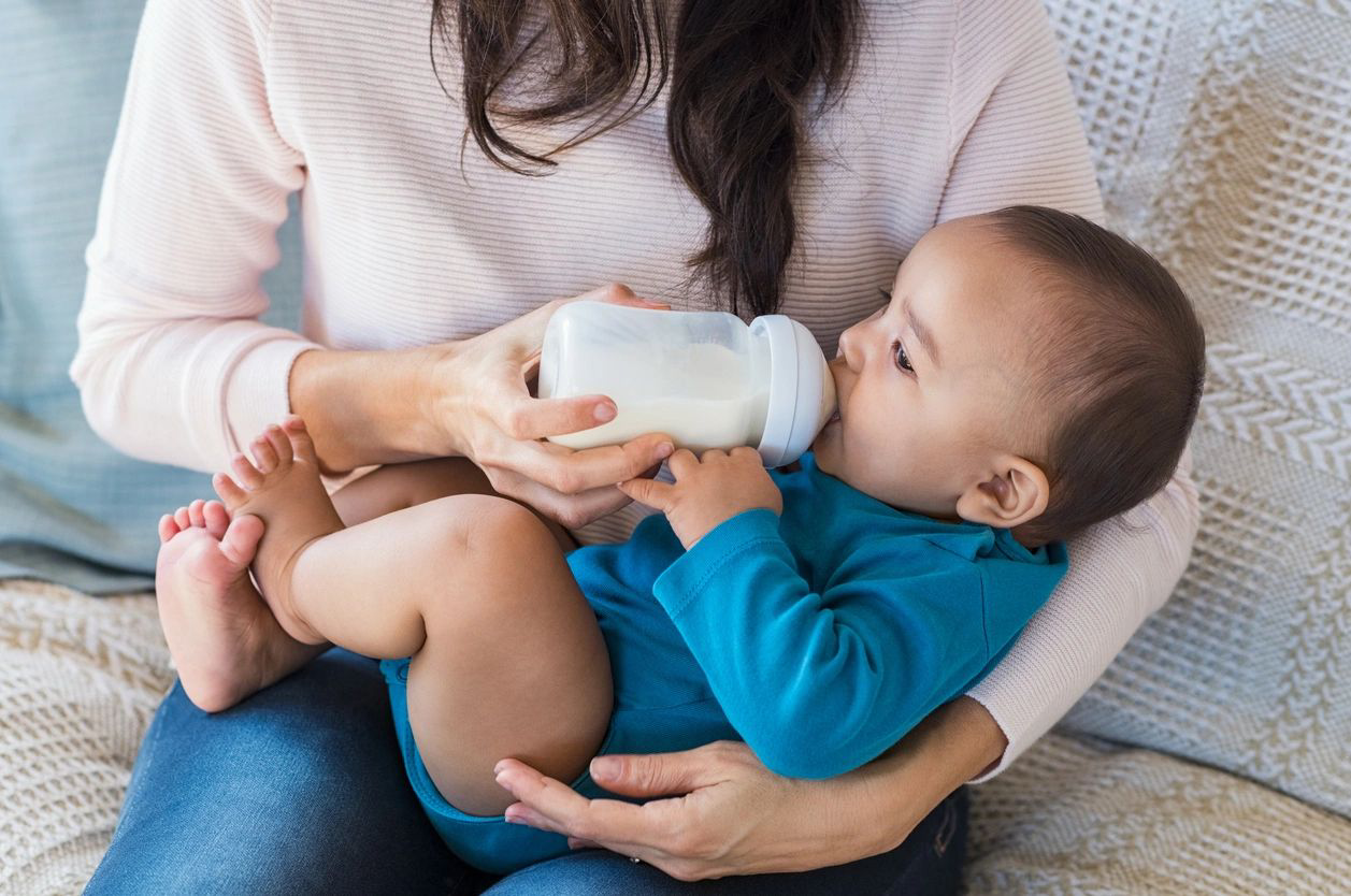 A woman is feeding a baby with a bottle.