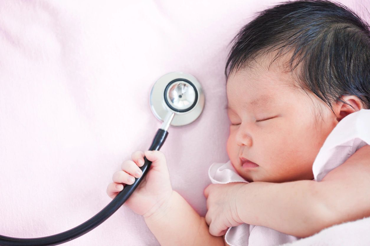 A baby is holding a stethoscope in its hand.