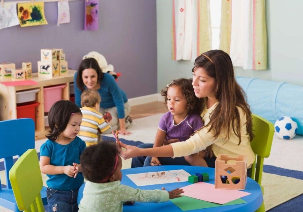 A woman is helping children with crafts.