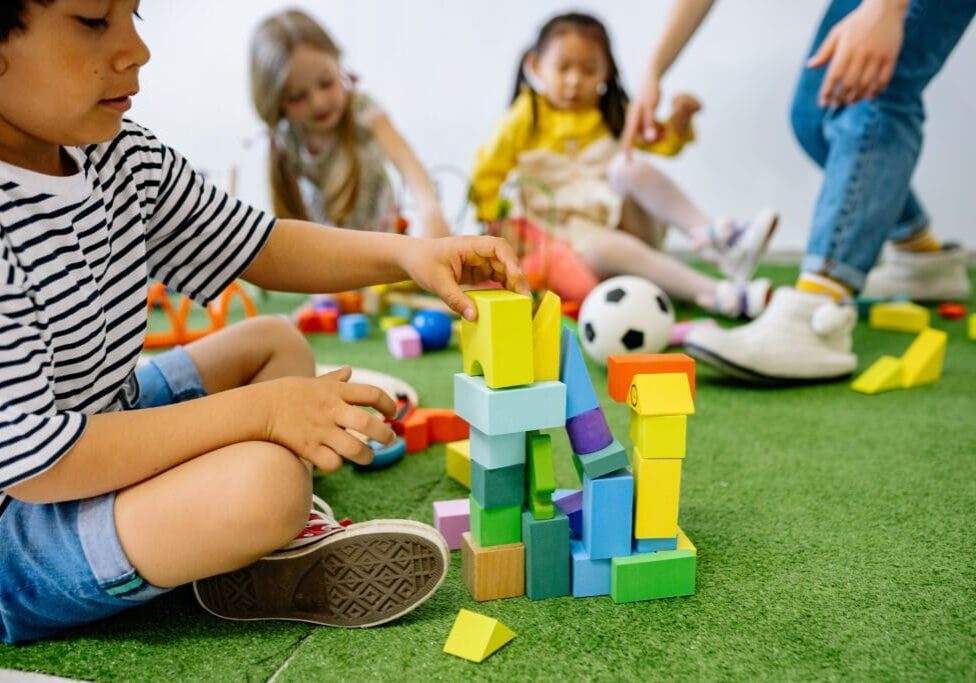 A group of children playing with blocks on the floor.